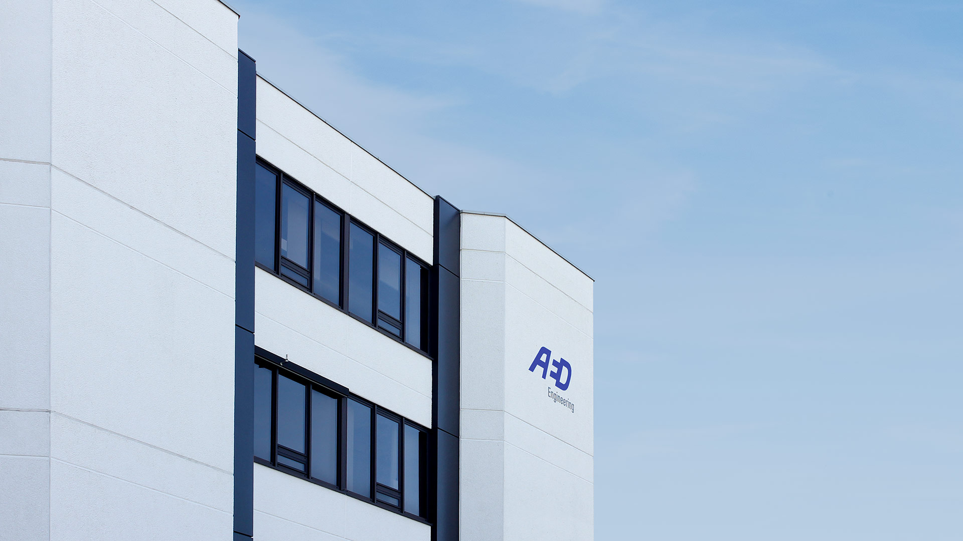 Fassadenbeschilderung mit dem Logo von AED Engineering an einer Gebäudefassade.